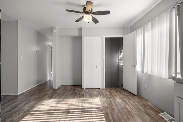 unfurnished bedroom with dark wood-style floors, a closet, visible vents, and ceiling fan