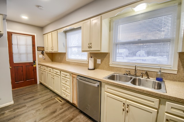 kitchen featuring tasteful backsplash, light countertops, stainless steel dishwasher, light wood-style floors, and a sink