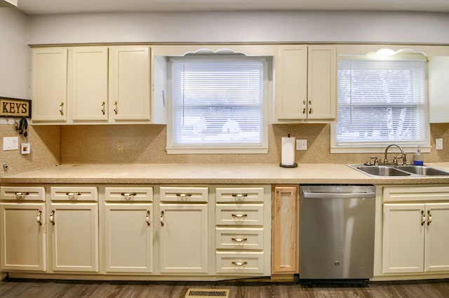 kitchen with light countertops, stainless steel dishwasher, a sink, and a wealth of natural light