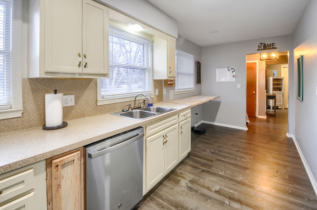 kitchen with baseboards, dishwasher, backsplash, wood finished floors, and a sink