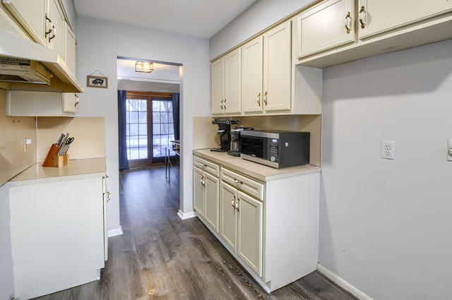 kitchen featuring dark wood-style floors, light countertops, stainless steel microwave, and baseboards