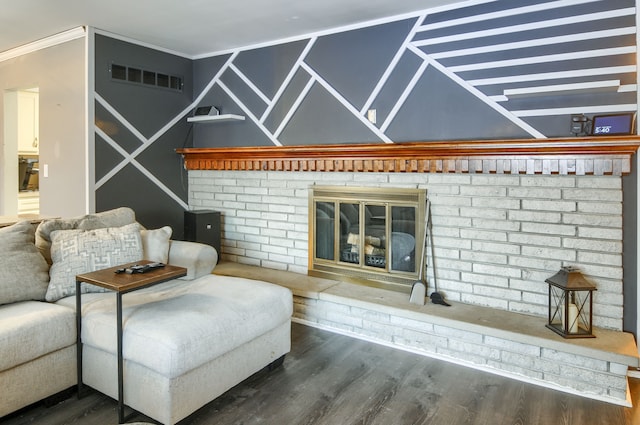 living room featuring crown molding, a fireplace, visible vents, and wood finished floors