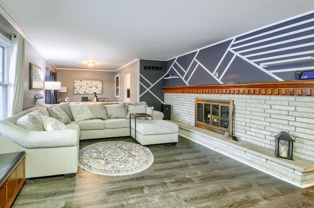 living room with a brick fireplace, crown molding, visible vents, and wood finished floors