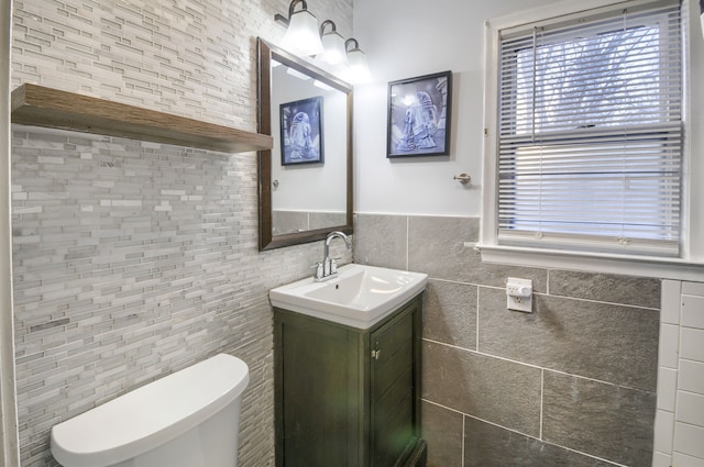 half bathroom featuring toilet, tile walls, and vanity