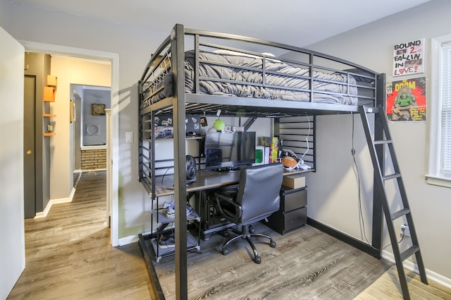 bedroom featuring wood finished floors, washer / dryer, and baseboards