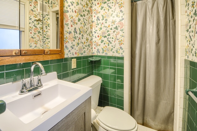 full bathroom featuring tile walls, wainscoting, toilet, and wallpapered walls