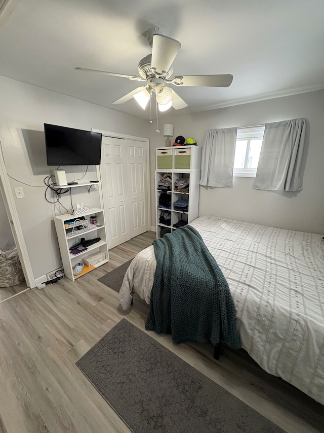 bedroom featuring a closet, wood finished floors, a ceiling fan, and baseboards