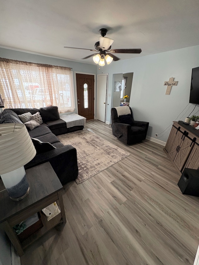 living room with a ceiling fan, baseboards, and light wood finished floors