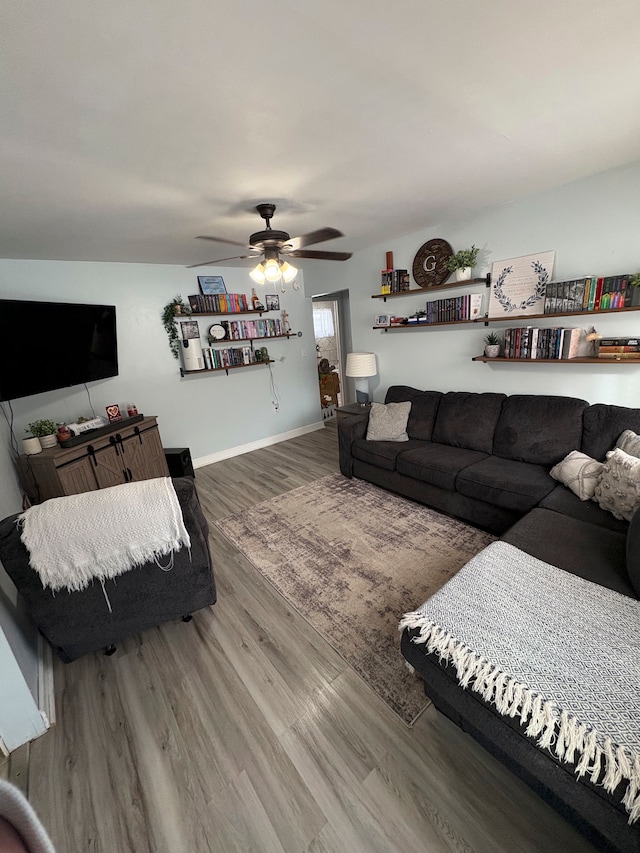 living area featuring ceiling fan, baseboards, and wood finished floors