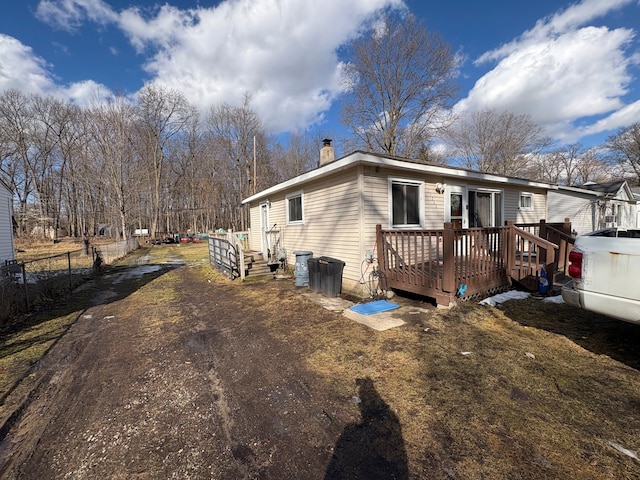 view of side of home with a chimney, fence, and a wooden deck