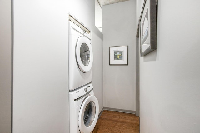 washroom featuring dark wood-style floors, laundry area, and stacked washer and clothes dryer