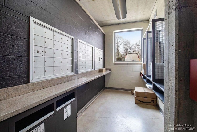 interior space with concrete block wall, mail area, and finished concrete floors