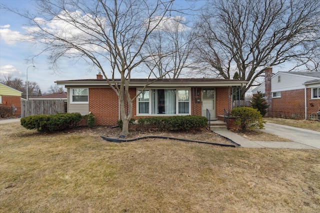 view of front facade with brick siding, a chimney, and a front lawn