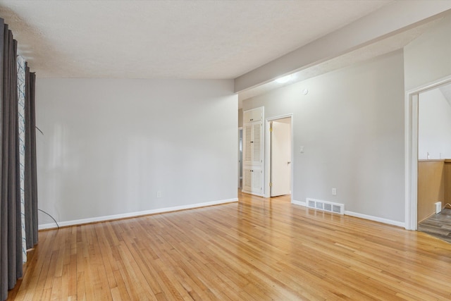 spare room featuring visible vents, light wood-type flooring, and baseboards