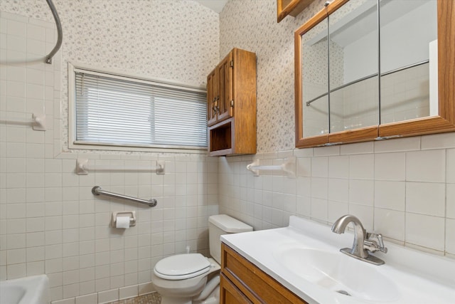 bathroom with wallpapered walls, toilet, wainscoting, vanity, and a shower