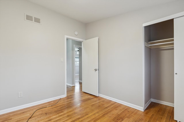 unfurnished bedroom featuring a closet, baseboards, visible vents, and light wood finished floors