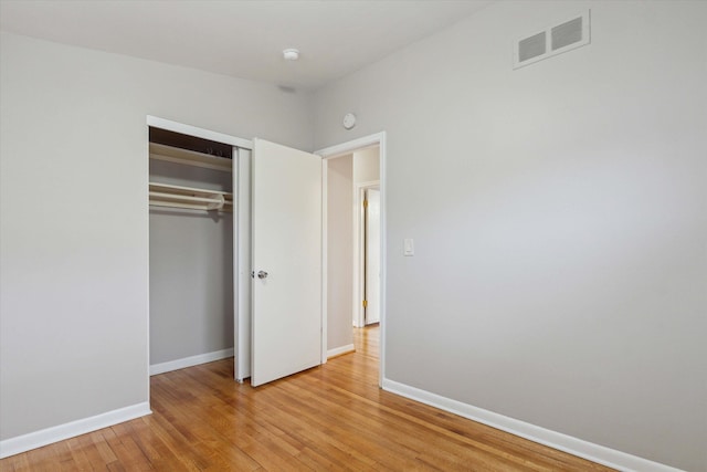 unfurnished bedroom featuring visible vents, baseboards, a closet, and light wood-style flooring