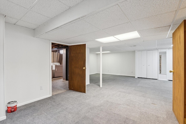 finished below grade area featuring a paneled ceiling, baseboards, washer / dryer, and carpet flooring