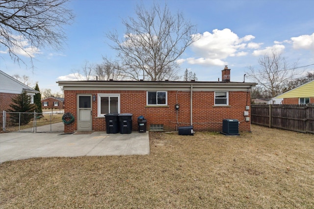 rear view of property featuring brick siding, a patio, a yard, and fence