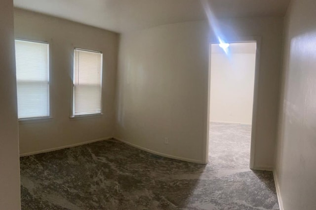 empty room featuring carpet and baseboards