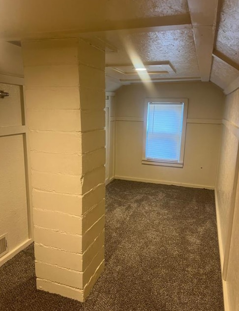 bonus room with dark colored carpet and vaulted ceiling