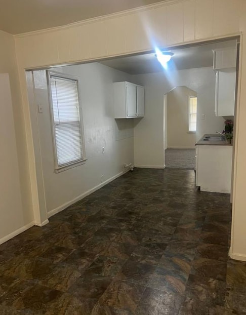 interior space with crown molding, a sink, and baseboards