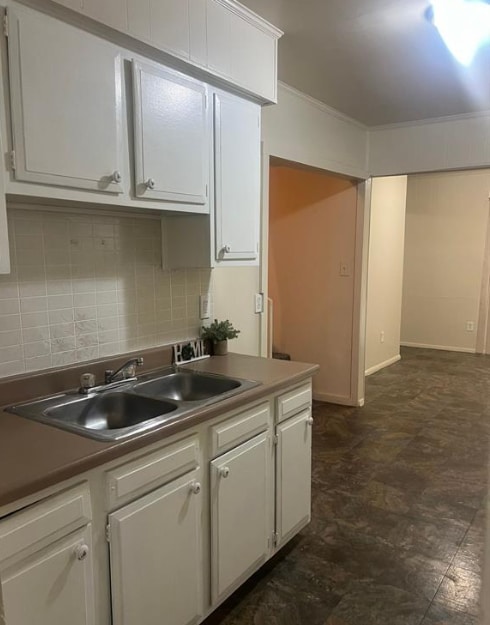 kitchen featuring white cabinetry, decorative backsplash, and crown molding