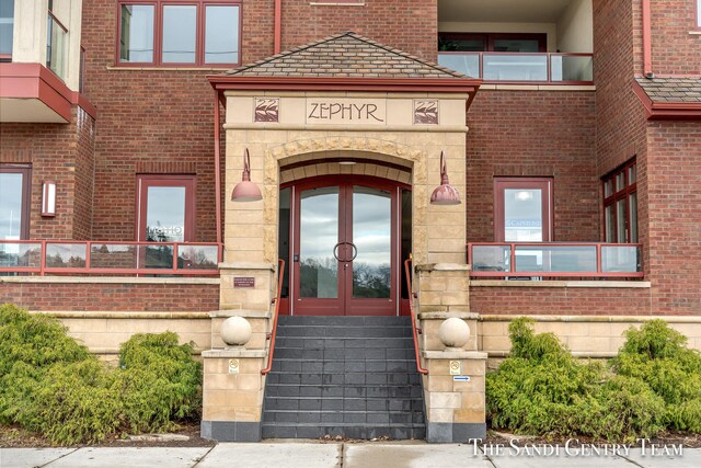 doorway to property featuring stone siding, french doors, and brick siding