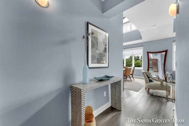 hallway featuring baseboards, vaulted ceiling, and dark wood-type flooring