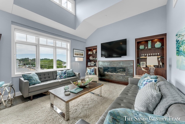 living area with a high end fireplace, baseboards, plenty of natural light, and a high ceiling