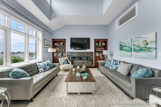 living room featuring vaulted ceiling, a fireplace, and built in features