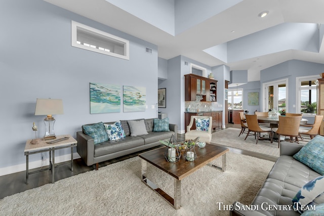 living area featuring high vaulted ceiling, recessed lighting, wood finished floors, visible vents, and baseboards