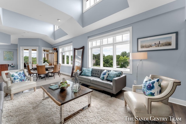 living room with french doors, vaulted ceiling, baseboards, and wood finished floors