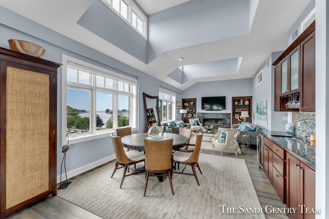 dining space featuring a fireplace, wood finished floors, visible vents, and baseboards