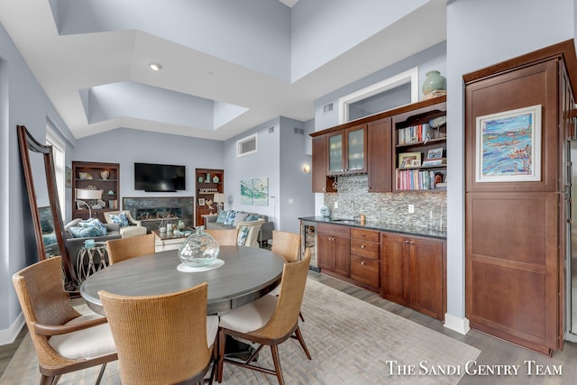 dining space featuring light wood finished floors, beverage cooler, a fireplace, and visible vents