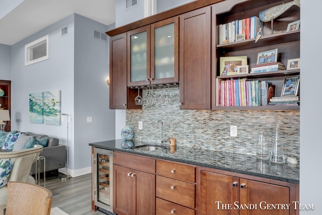 kitchen featuring dark stone counters, wine cooler, visible vents, and glass insert cabinets