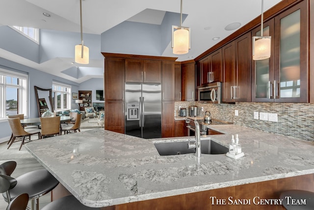 kitchen with hanging light fixtures, a sink, appliances with stainless steel finishes, and glass insert cabinets