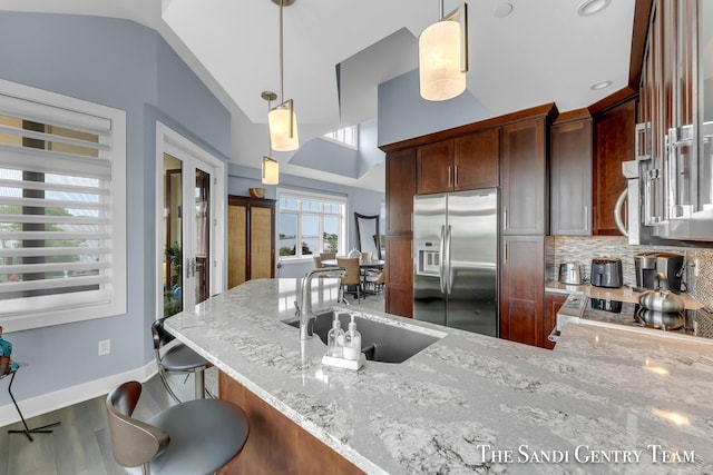 kitchen with hanging light fixtures, a peninsula, stainless steel appliances, and a sink