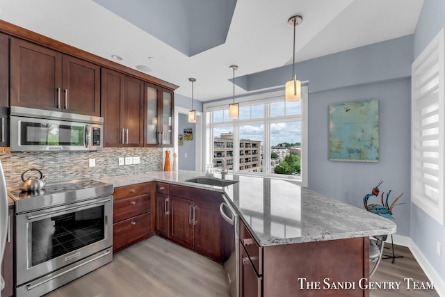 kitchen with light stone counters, decorative light fixtures, decorative backsplash, appliances with stainless steel finishes, and glass insert cabinets