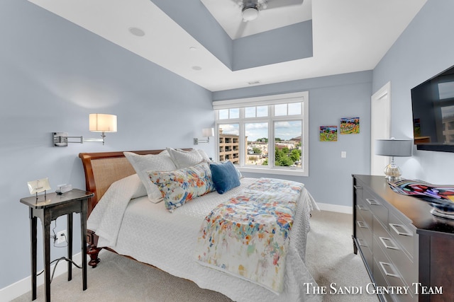 bedroom with a raised ceiling, light carpet, and baseboards