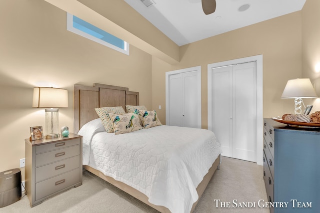 bedroom featuring multiple closets, light carpet, and ceiling fan