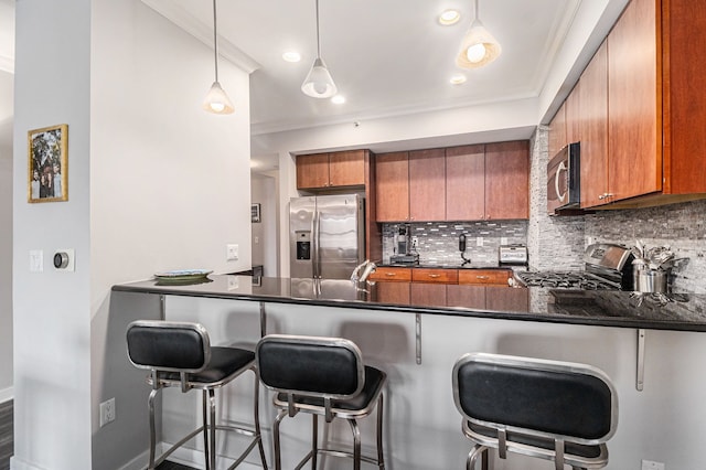 kitchen featuring dark countertops, a peninsula, brown cabinets, and stainless steel appliances