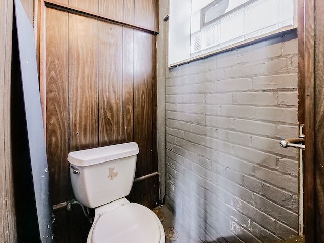 bathroom featuring toilet and brick wall