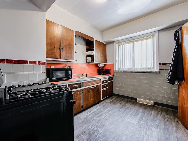 kitchen with visible vents, wood finished floors, black appliances, open shelves, and a sink