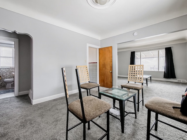 living area featuring arched walkways, carpet flooring, and baseboards