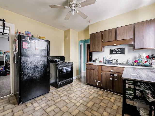 kitchen with ceiling fan, stone finish flooring, a sink, light countertops, and black appliances