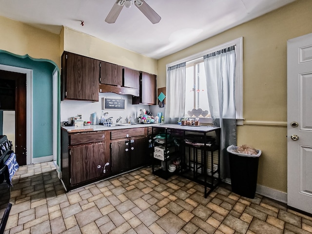 kitchen featuring light countertops, dark brown cabinets, a sink, and baseboards