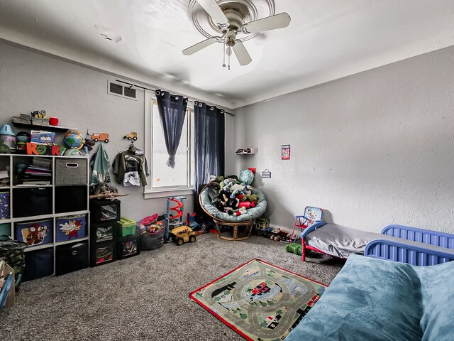 carpeted bedroom featuring a textured wall, visible vents, and a ceiling fan