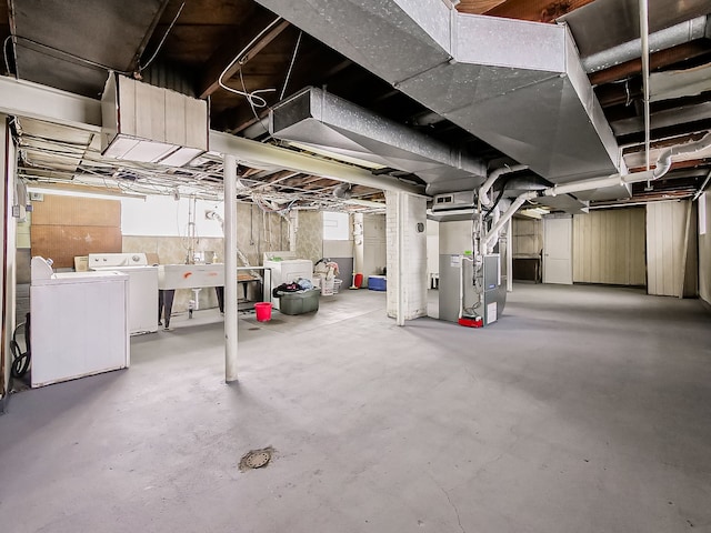 unfinished basement featuring heating unit, a sink, and independent washer and dryer