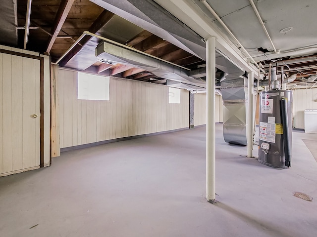 basement featuring washer / clothes dryer, water heater, heating unit, and a healthy amount of sunlight